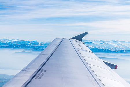 airplane wing with blue and white sky background