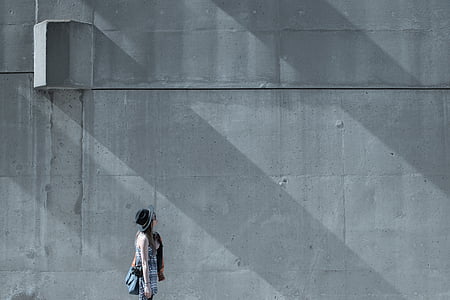 woman standing beside gray wall