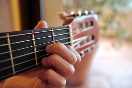 person holding brown classical guitar