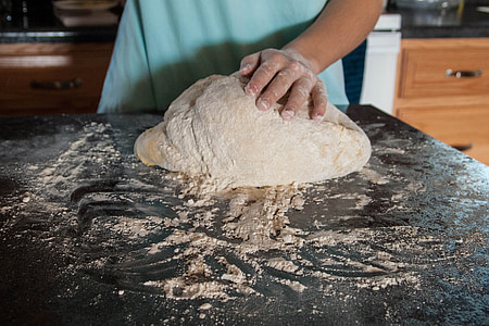 person mixing dough with flour
