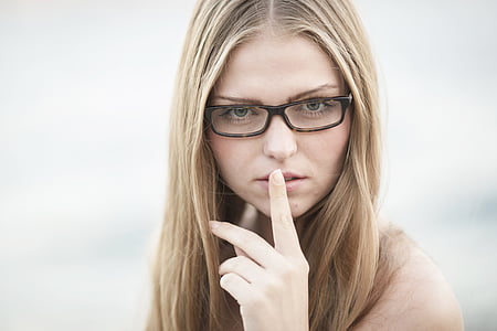 woman wearing black eyeglasses with index finger on her lips