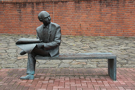 man sitting on bench holding paper statue