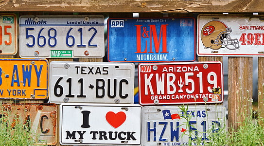 assorted vehicle plates on wooden fence