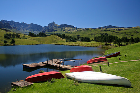 several assorted-color kayaks on green grass fields under blue calm sky