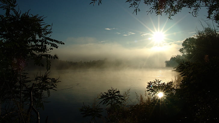 body of water with fog during sunrise