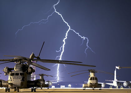 black helicopters near body of water during lightning