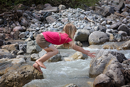 girl at rock jumping and reaching another stone