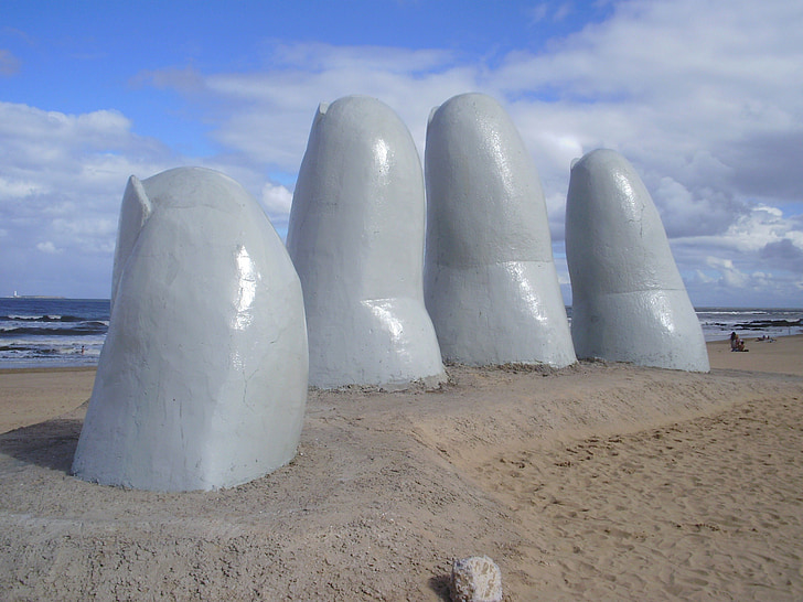 hand monument near beach at daytime
