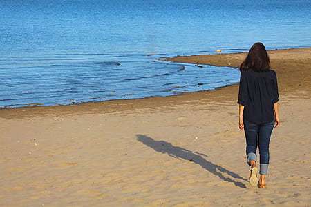 woman wearing blue denim jeans walking on a seashore