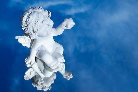 white ceramic cherub figurine reflects on blue water