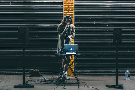 DJ holding microphone in front of MacBook on stage