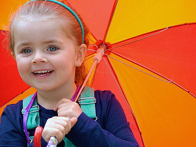 girl wearing gray long-sleeved shirt white smiling holding yellow and red umbrella