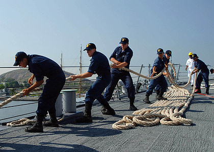 group of men pulling rope on ship deck