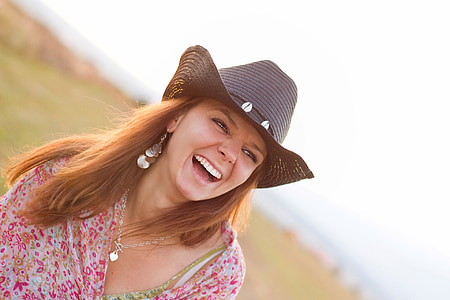 selective focus photo of happy woman wearing red and white floral top and black hat