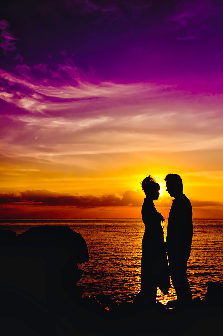 silhouette of man and woman standing on seashore