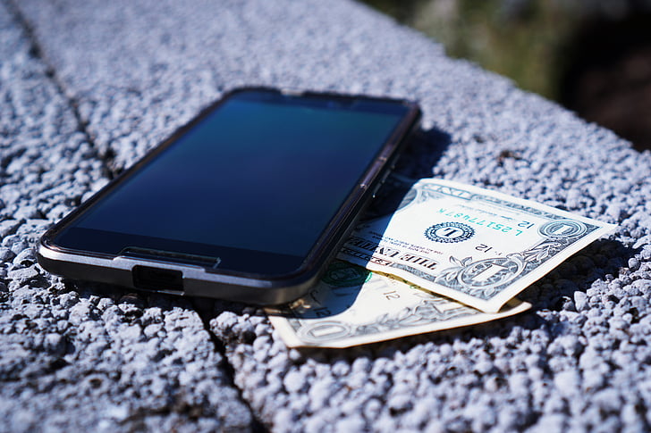 selective focus photographyt black Android smartphone and two 1 U.S. dollar banknotes