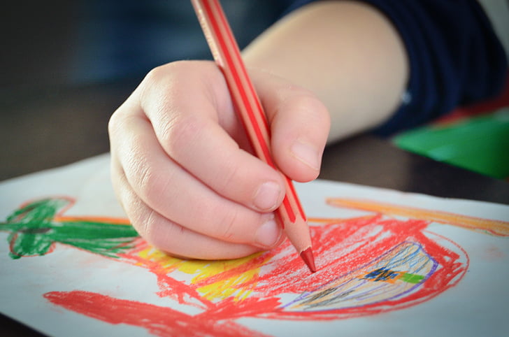 person holding red colored pencil in shallow focus photography