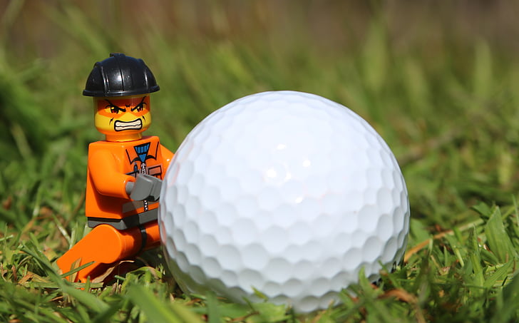 orange LEGO character minifig near golf ball
