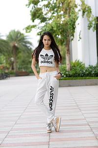 black haired woman wearing Adidas crop-top and sweatpants with pair of silver platform sneakers