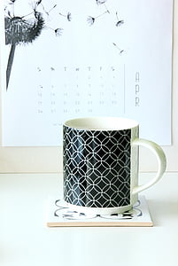 white and black ceramic mug on white coaster
