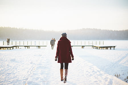 woman wearing red coat and brown leggings walking during winter