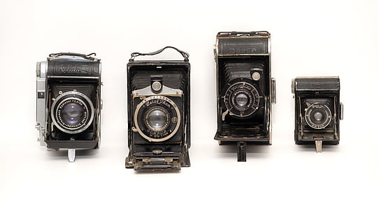 four black folding cameras on white surface