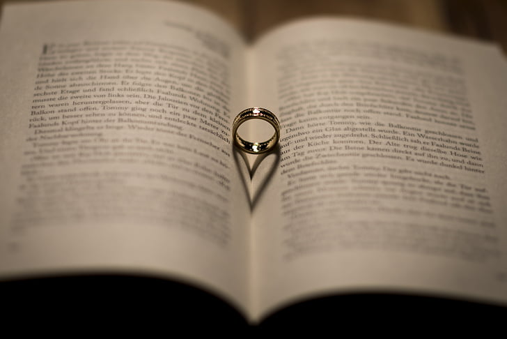 silver-colored ring on whit opened book