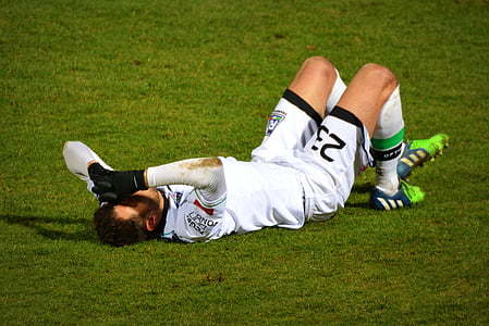 man in soccer jersey laying on green grass