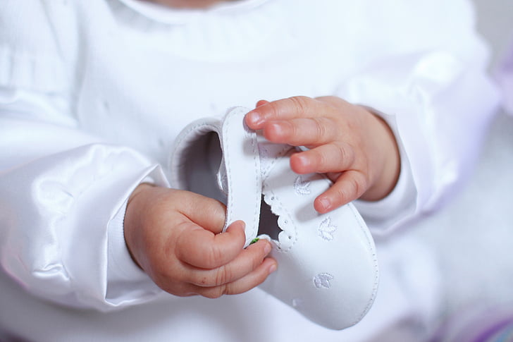 photo of baby holding white shoe