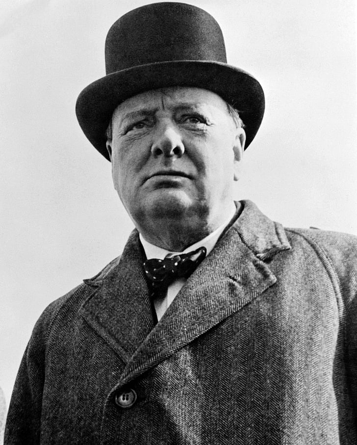 grayscale photograph of man wearing coat and hat