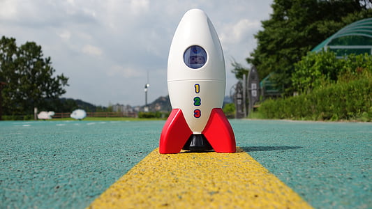 white toy rocket on cement pavement