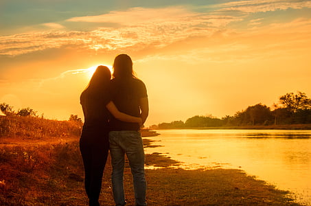 couple embracing each other looking on sunset