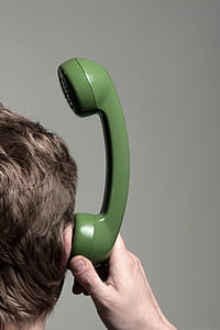 man holding green telephone headset near his ears