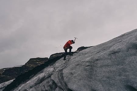 man holding pickaxe on gray rock