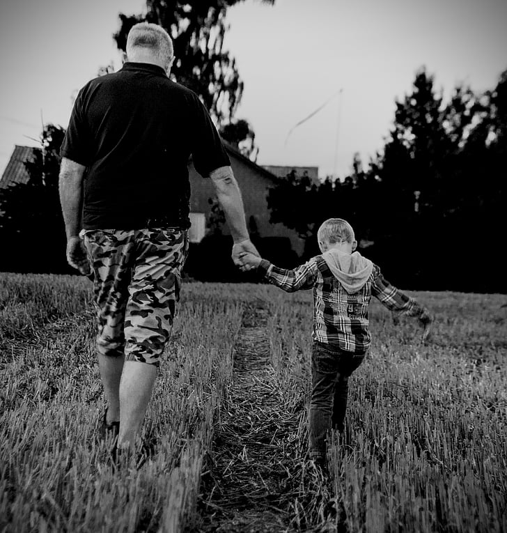 man holding boy walking on grass