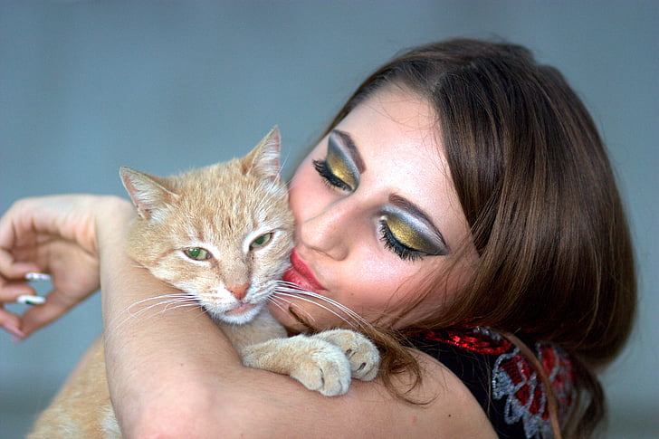woman kissing orange tabby kitten