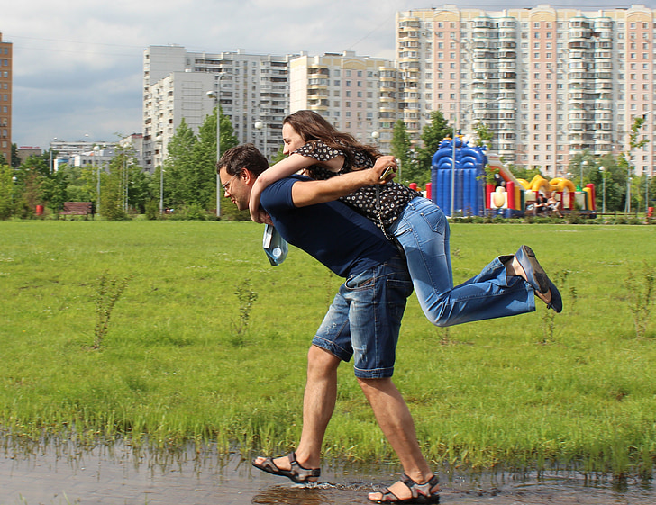 man carrying woman in his back while walking on water