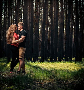 photographed of man holding woman standing near trees