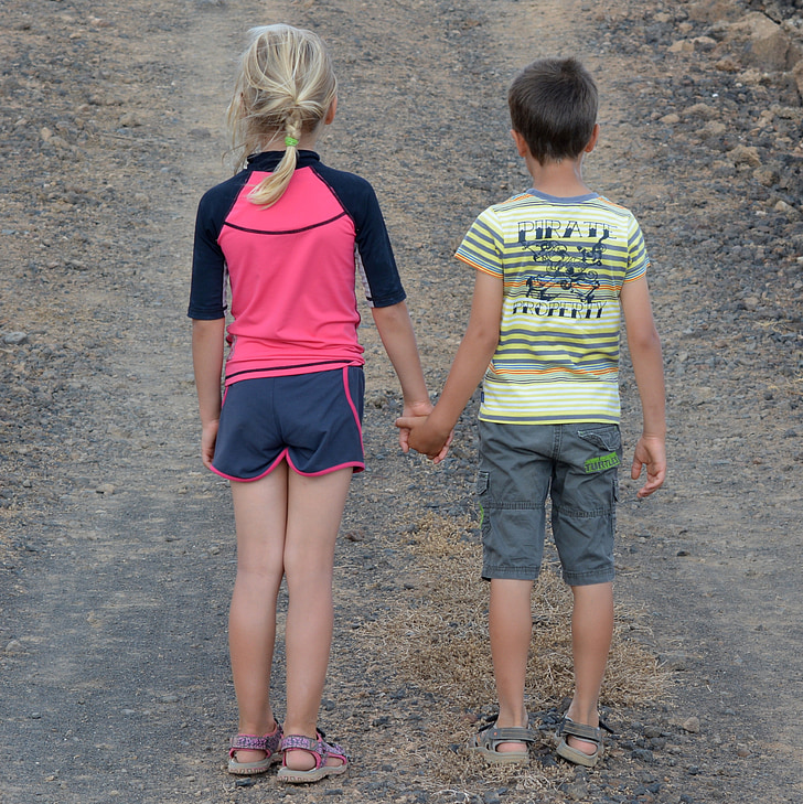 boy and girl holding hands during daytime