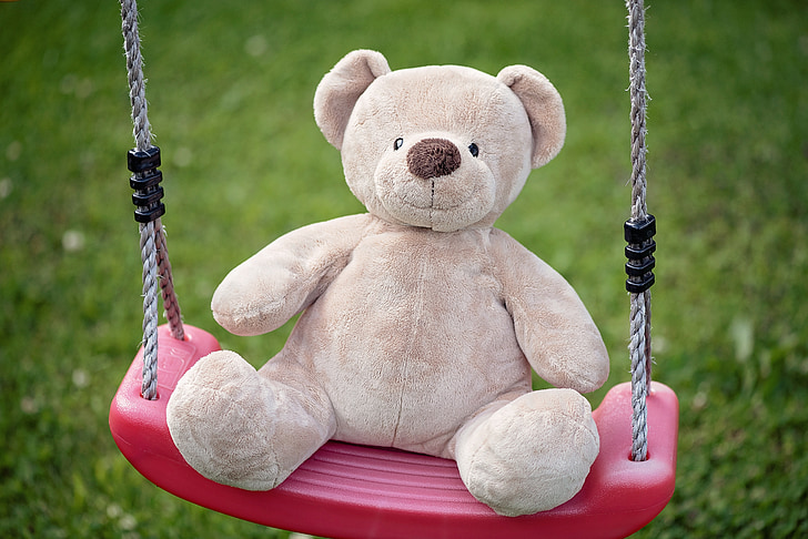 bear plush toy on pink swing