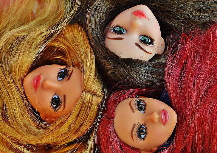 close-up photo of three girl dolls