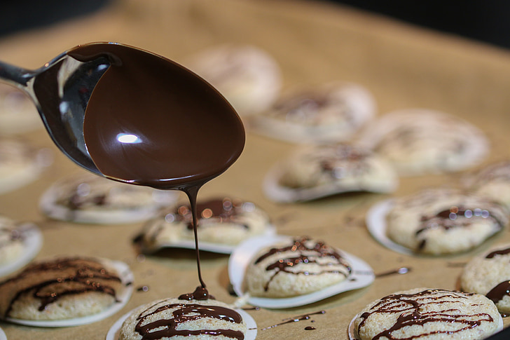 depth of field photography of chocolate dripping through spoon towards cookie