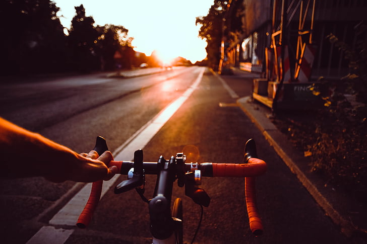 person riding on road bicycle during sunset