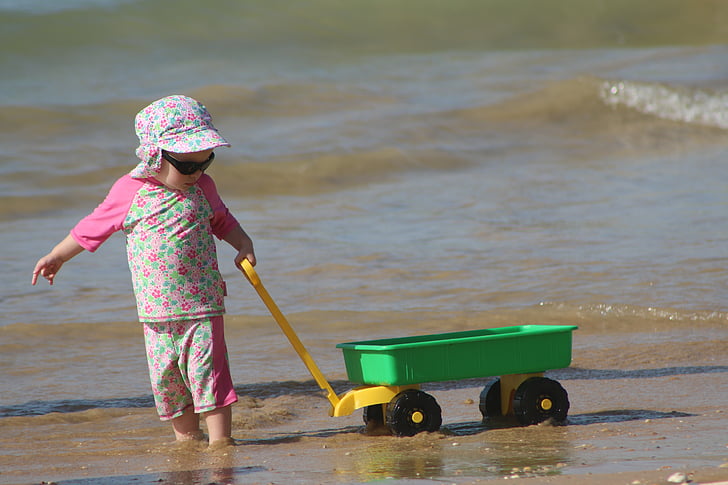 child pulling wagon on shore