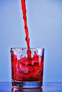 pouring red beverage in clear rocks glass