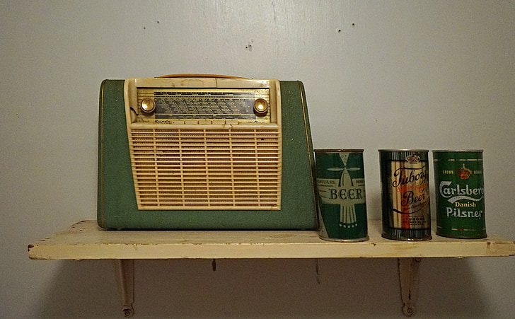 green and brown transistor radio beside three assorted cans