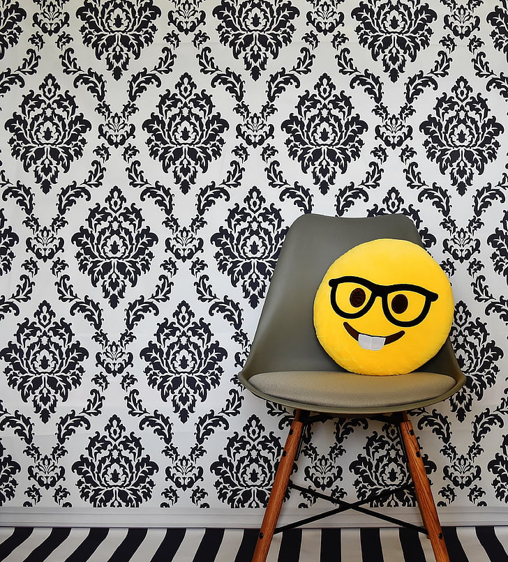 yellow emoji pillow on brown wooden framed gray padded chair