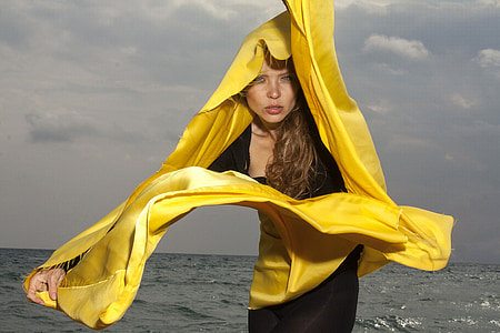 woman in black dress and yellow scarf near body of water at daytime