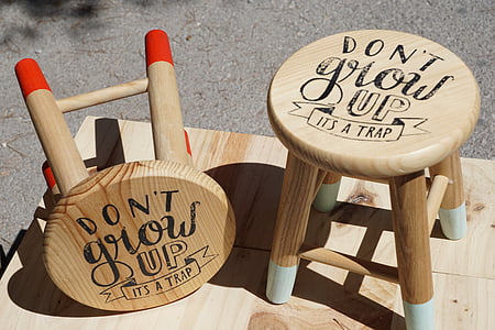 two round beige don't grow up-printed wooden stools on beige wooden board