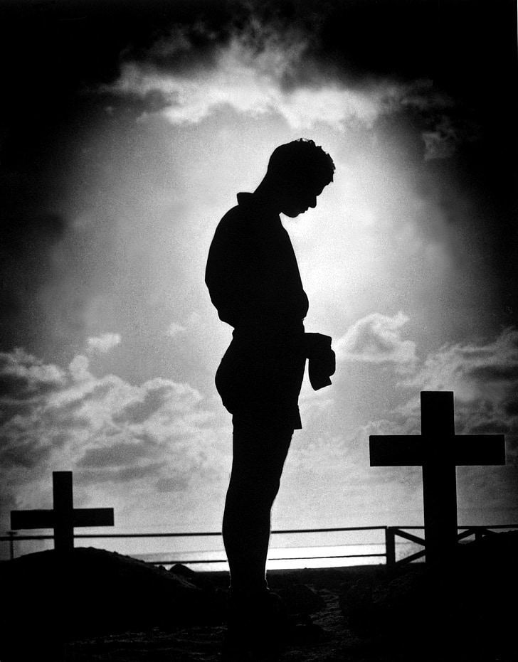 silhouette of man standing beside cross